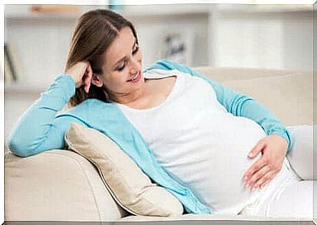 A pregnant woman laughs while touching her belly