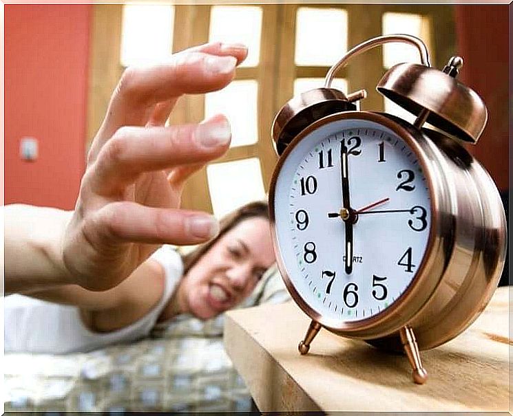 Woman who angrily turns off her alarm clock