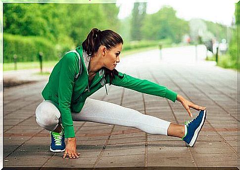 Woman in green and white sports suit is stretching